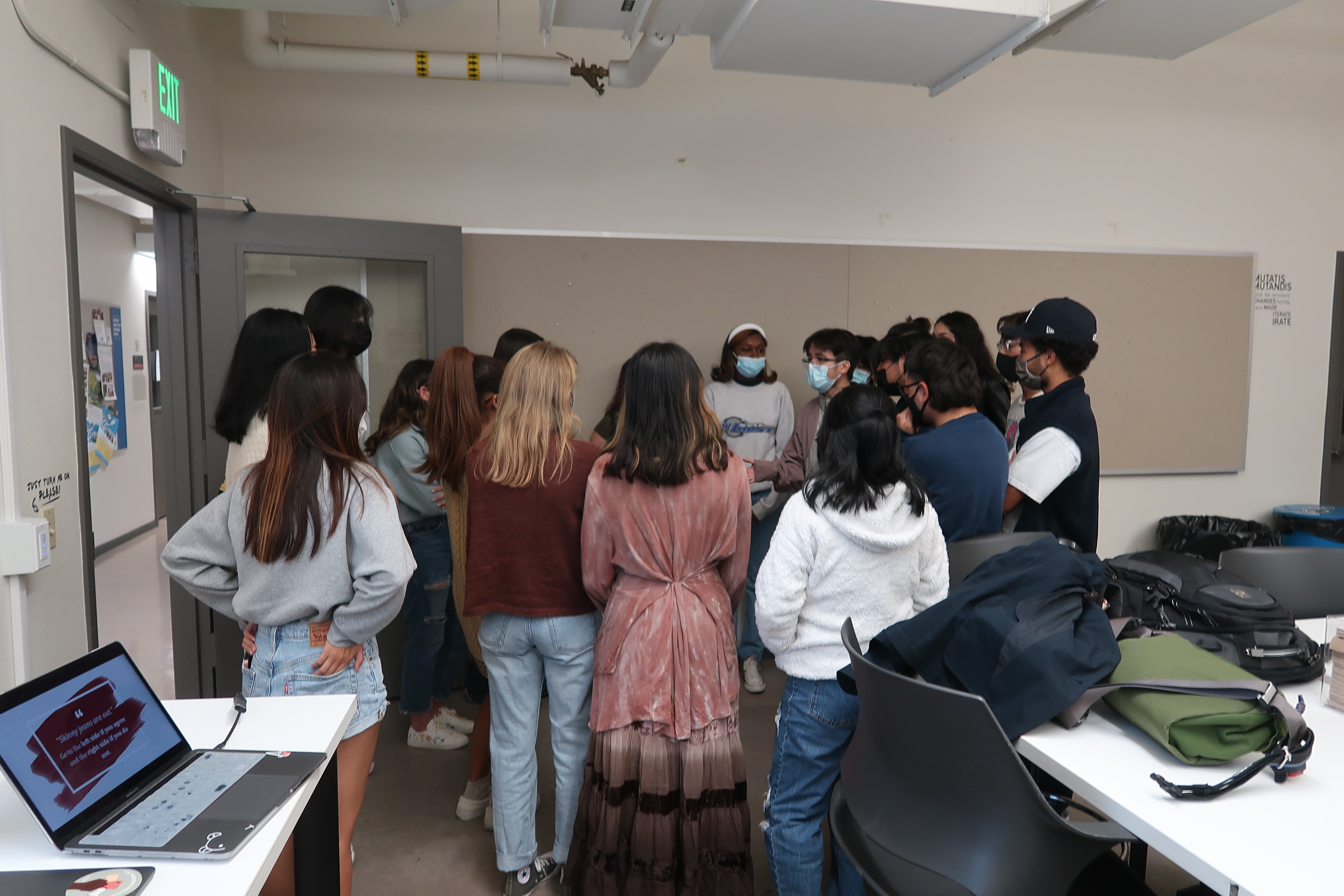 Students gathering in back of fashion room to debate a fashion topic.